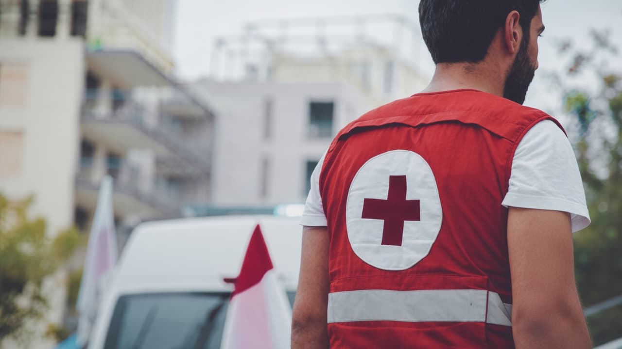 Lebanese Red Cross volunteer seen from behind, red vest with a red cross on the back